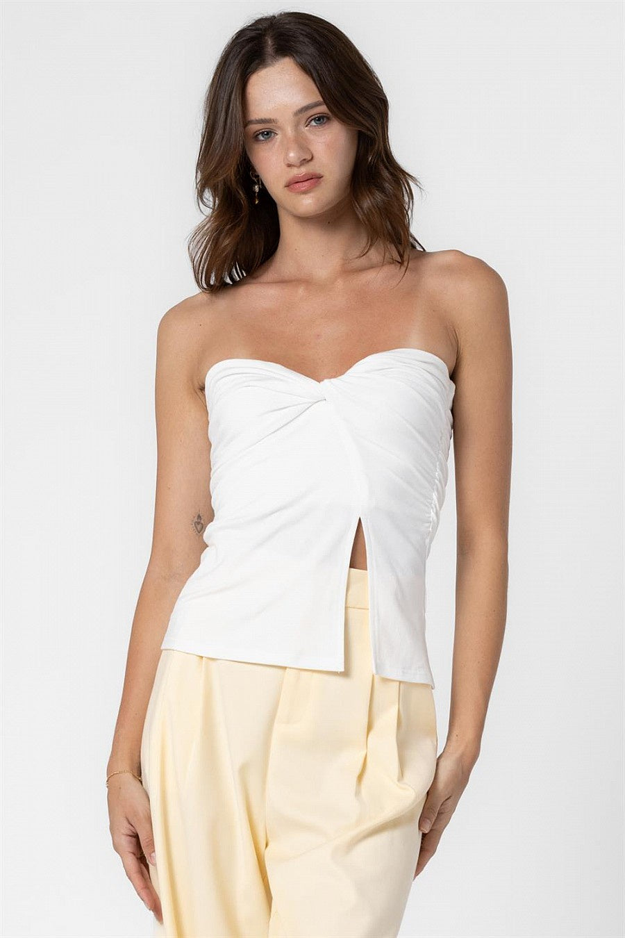 Featuring a twist front tube top with a side slit detail in the color off white 