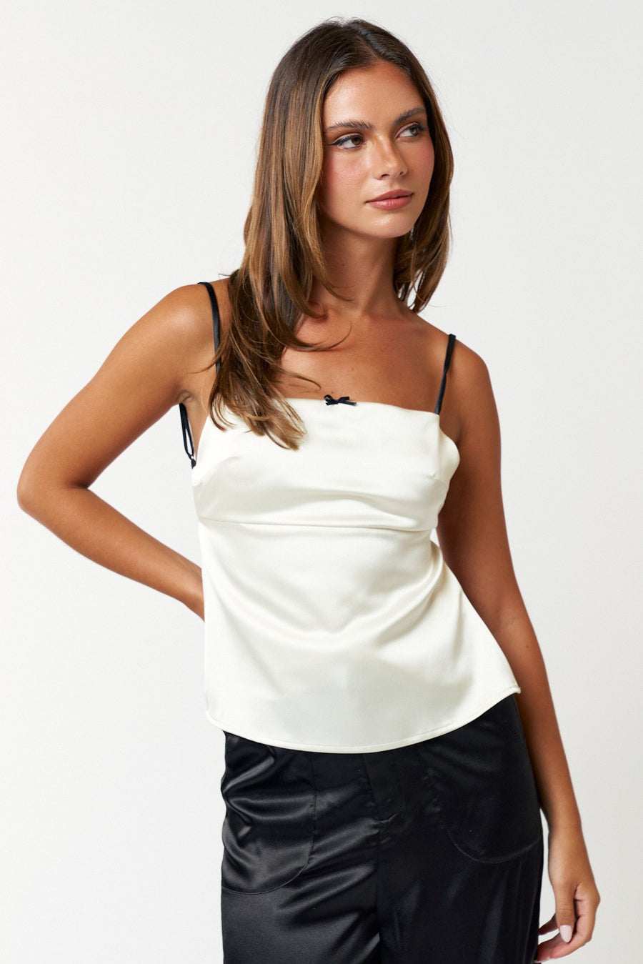Featuring a contrast strap open back satin tank with a bow detail on the front In the color off white 