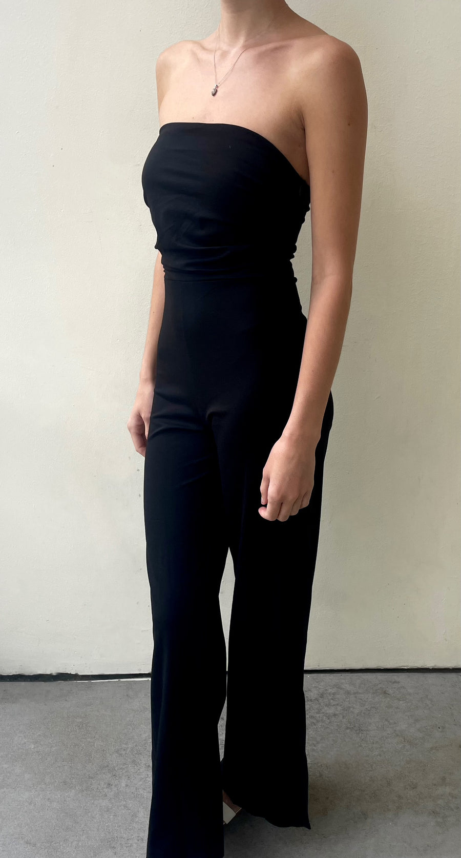Featuring a strapless stretchy jumpsuit with small slits on the side of each leg in the color black 
