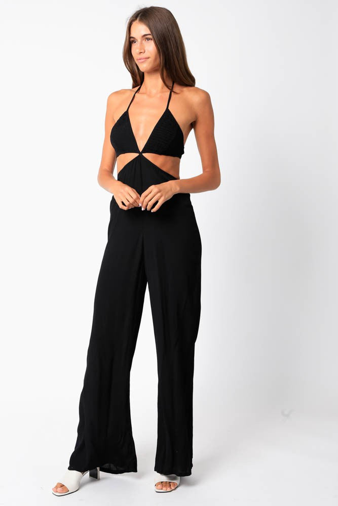 Model is wearing a black jumpsuit with side cut outs and thin straps (halter style).