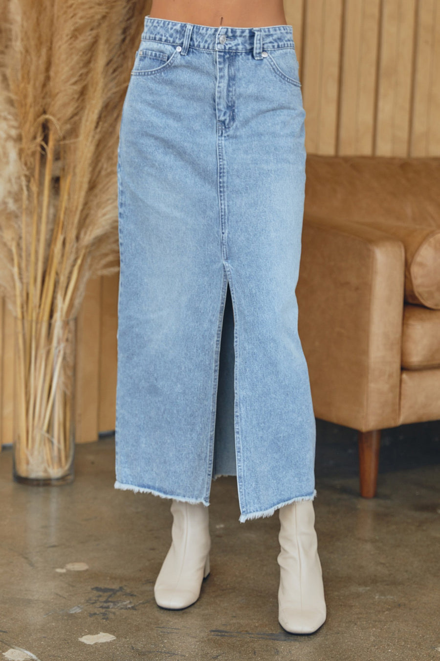 Featuring a light wash denim midi skirt with pockets and a front slit detail in the color light denim