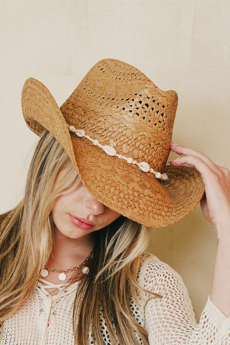 Featuring a straw woven cowboy style hat with a shell lined belt in the color brown 
