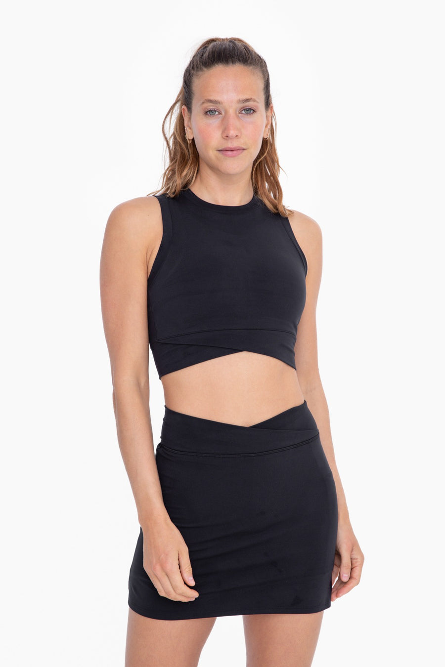 Featuring a high neck cropped tank with a front crossover detail and built in bra in the color black 