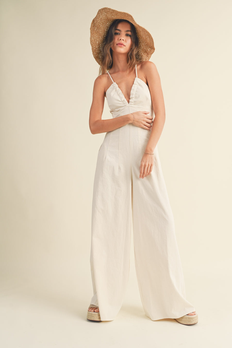 Featuring an open back V-neck Jumpsuit with a wide leg and pockets on each side in the color ecru