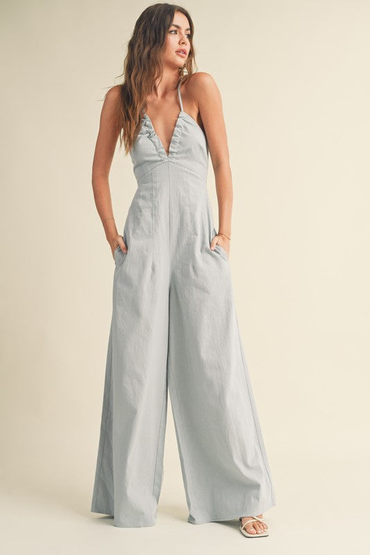 Featuring an open back V-neck Jumpsuit with a wide leg and pockets on each side in the color Light Denim