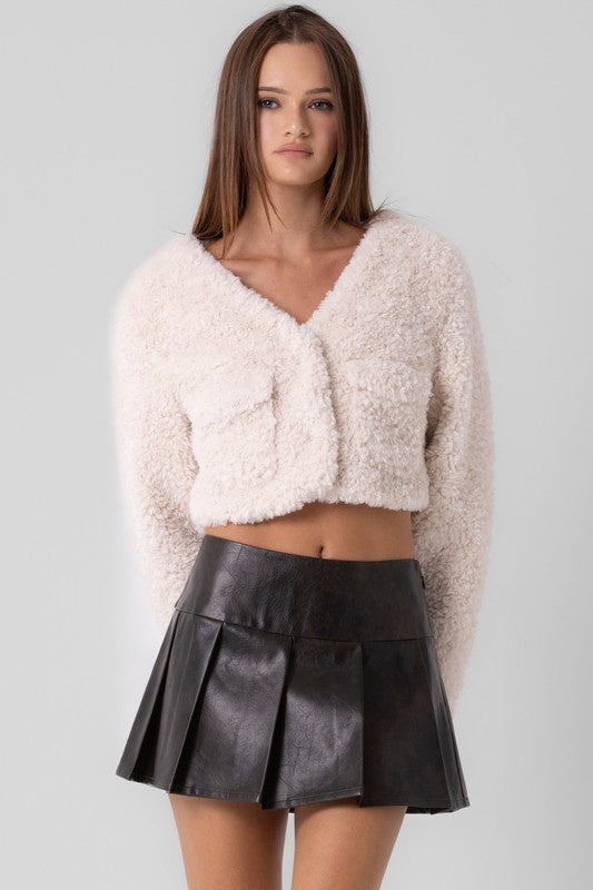 Featuring a woven faux fur boucle cropped long sleeve jacket in the color cream