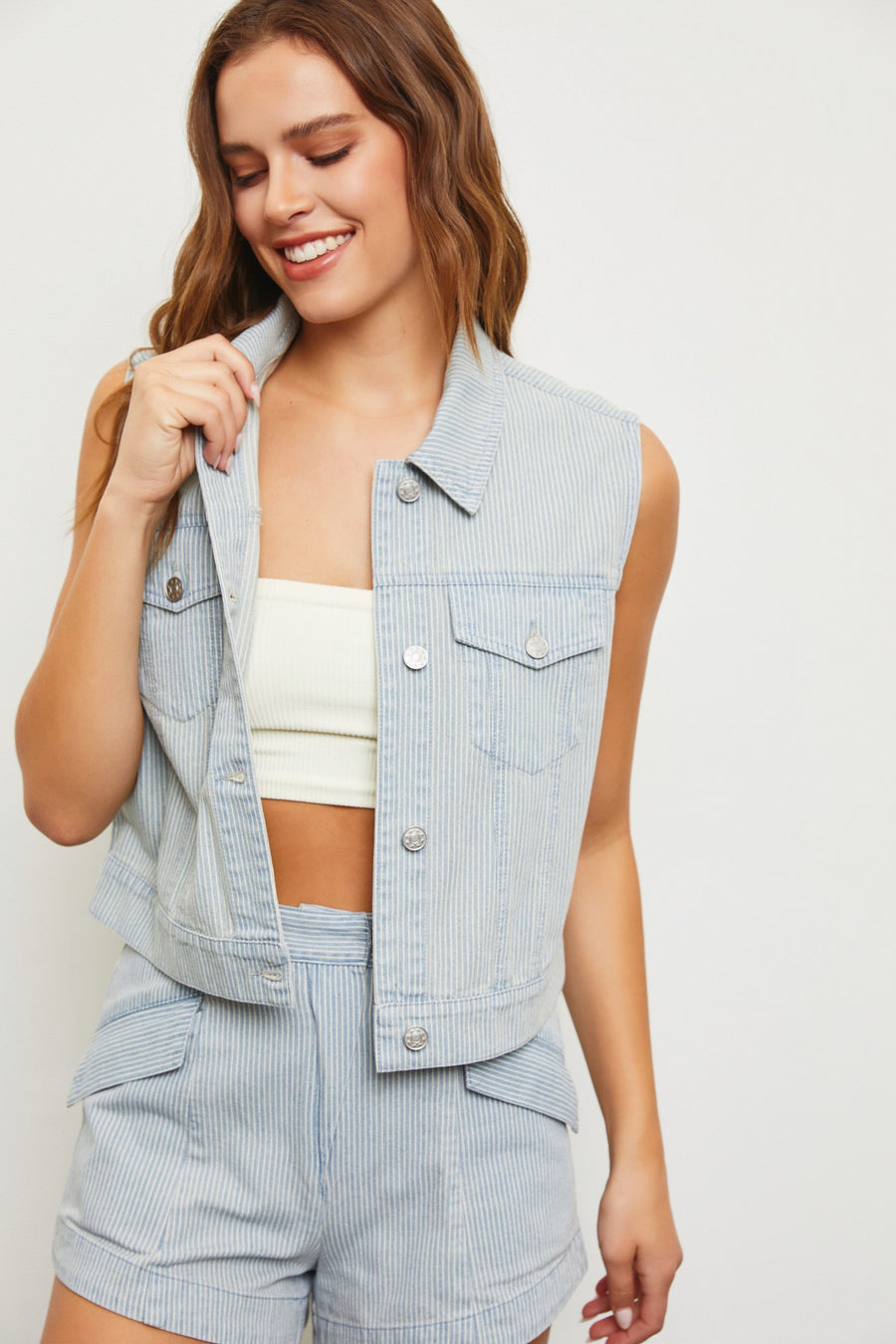 Featuring a stripped button up denim vest with two front pockets in the shade light denim