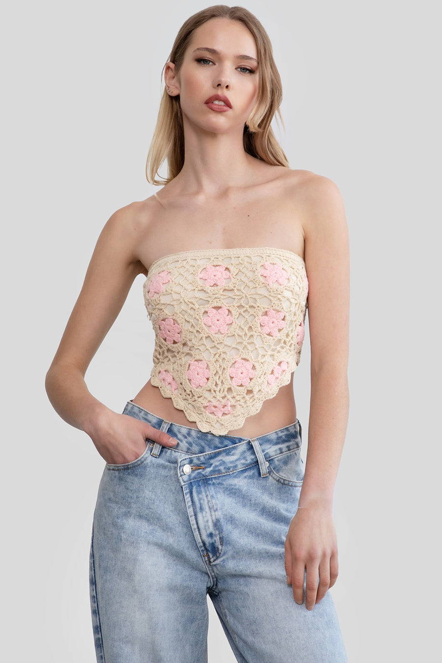Featuring a flower pattern strapless crochet top with a lace up back and an Asymetrical hem in the color natural with pink flowers 