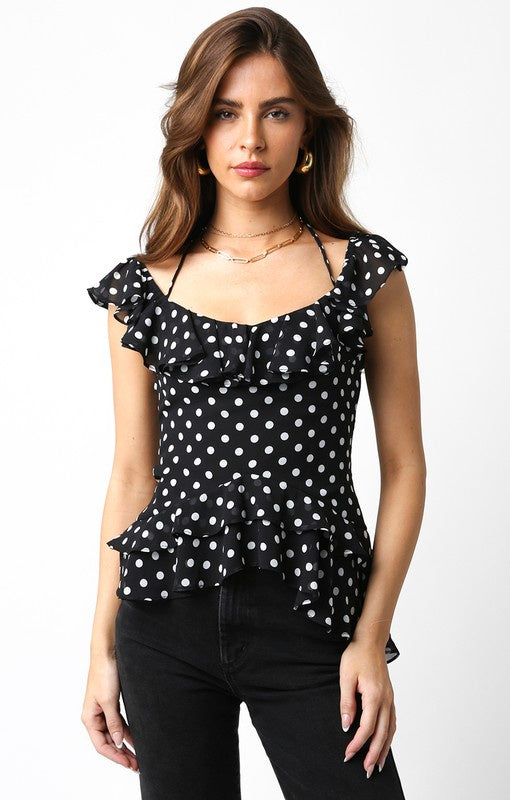 Featuring an open back polka dotted ruffle top in the color black and white 