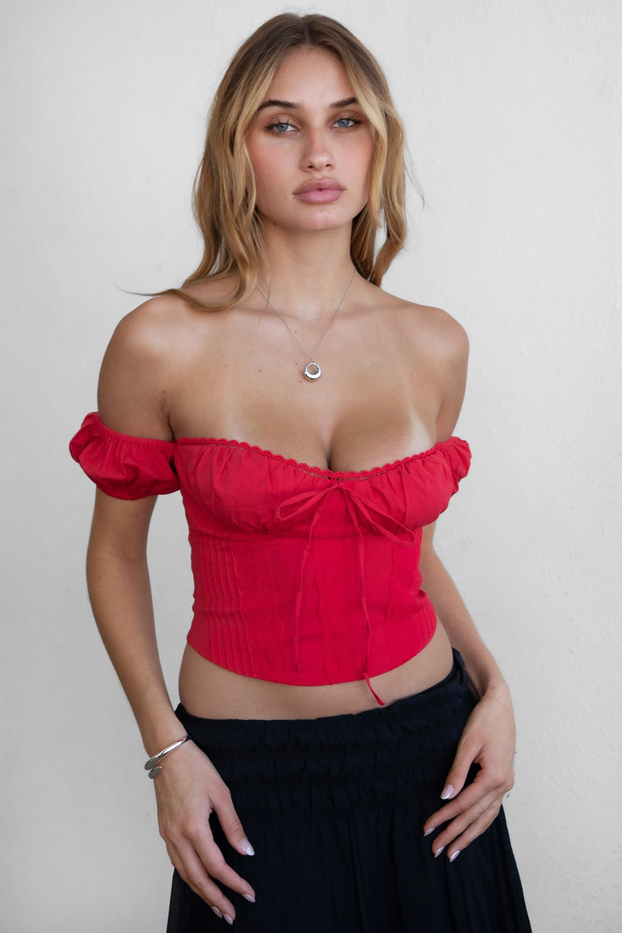 Featuring an off shoulder tie front crop top with a front lace over lay and a tie up back in the color red 