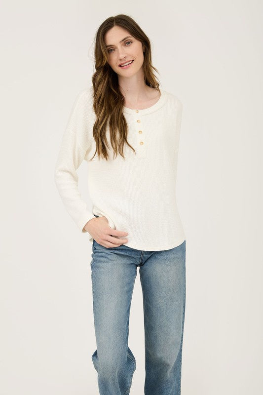 Featuring a long sleeve crew neck partial button up top in the color cream 