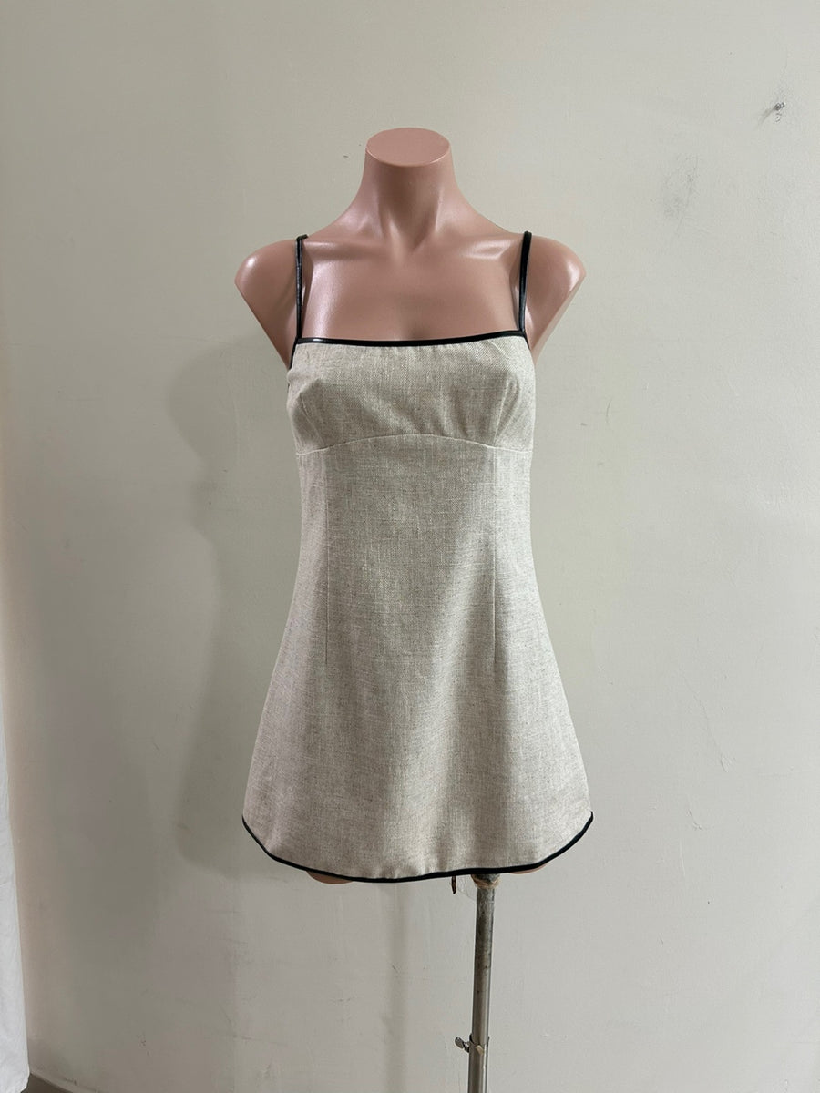 Featuring a beige linen mini dress with black trim and spagetti straps