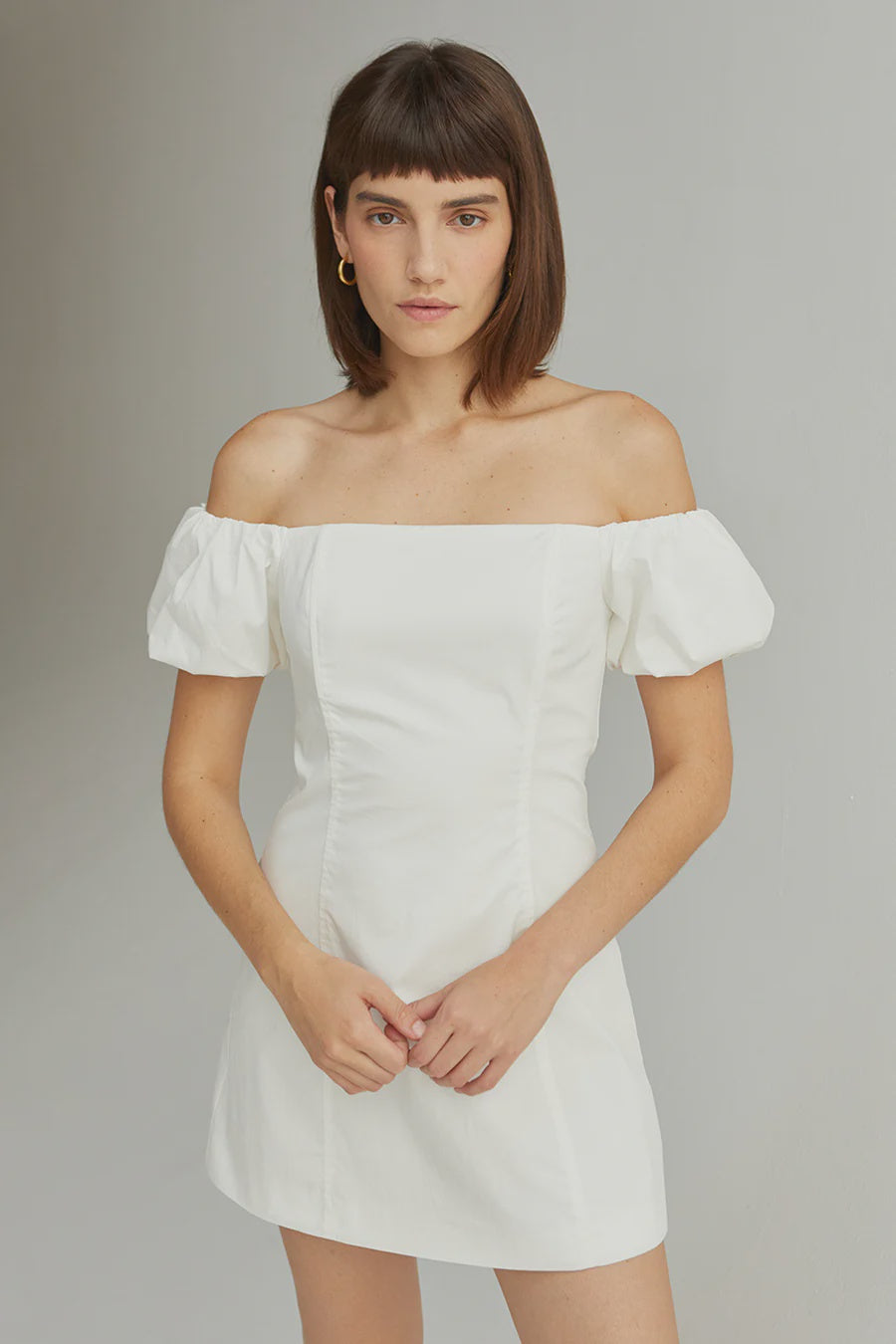 Featuring a puff sleeve off shoulder mini dress with a zip closure on the back in the color white