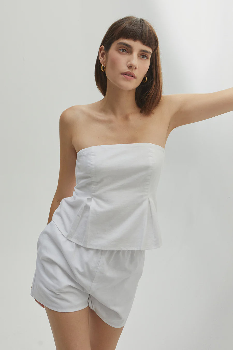 Featuring a flare tube top with two front pleats and a back zipper in the color white 