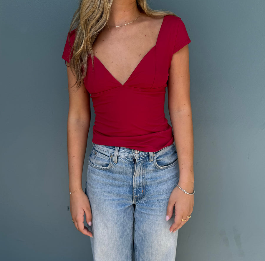 Featuring a fitted short sleeve V-neck top in the color cherry 