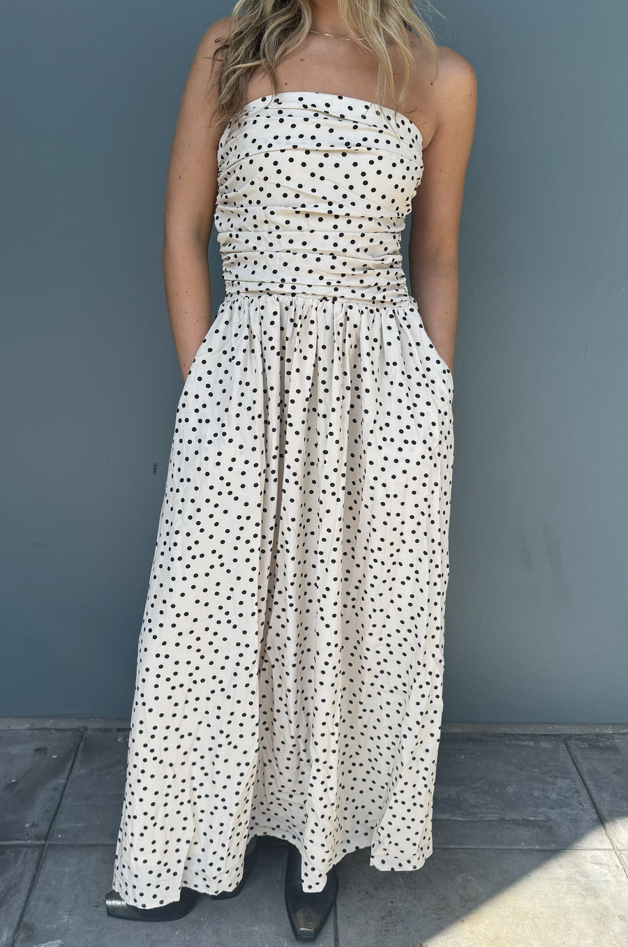 Featuring a flowy polka dotted strapless maxi dress with a side zip closure and an elastic back in the color cream 