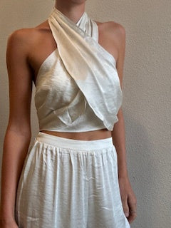 Featuring a satin halter top in a cream color with matching pants