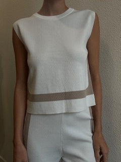 Featuring a sleeveless, tie back white top with beige detailing and matching pants.