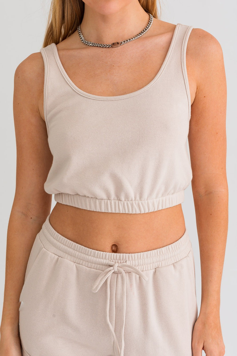 Cropped tank top with waistband in the color cream.