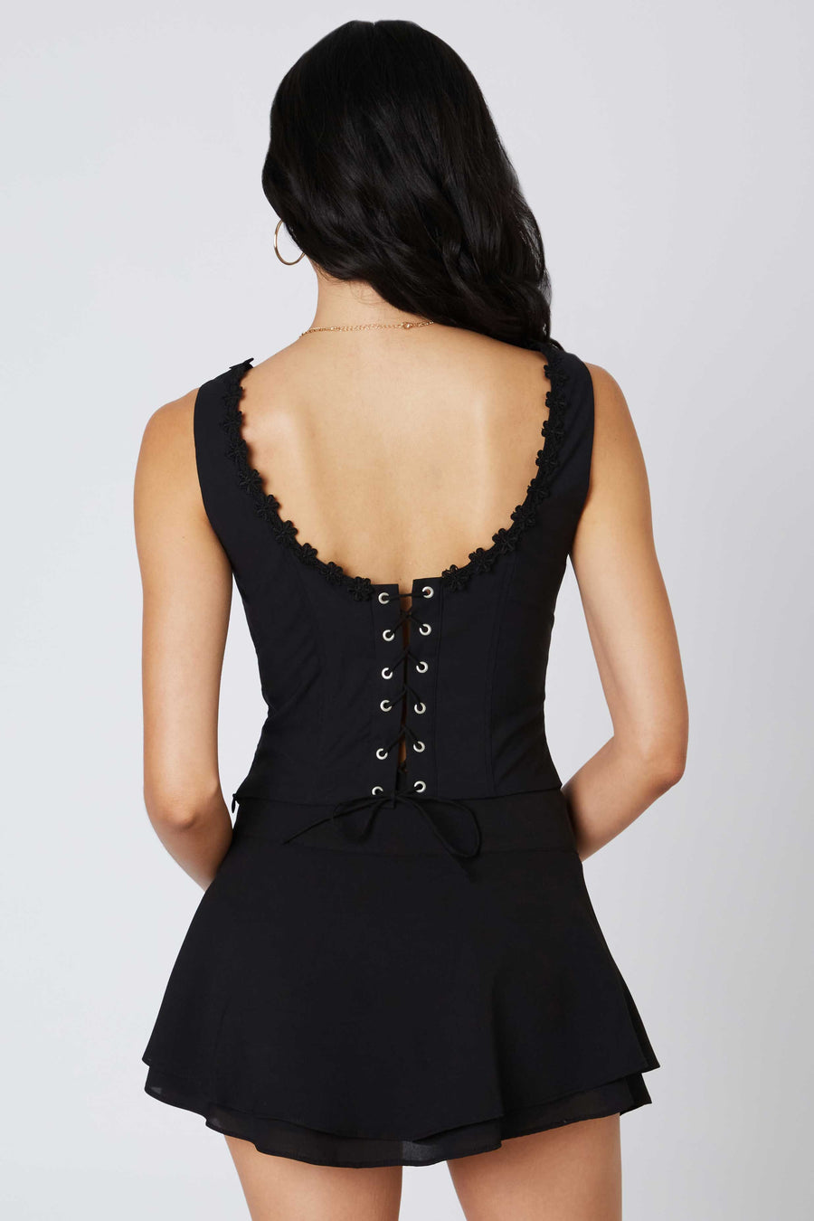 Cropped, lace-up top with thick straps and flower details along the neckline.