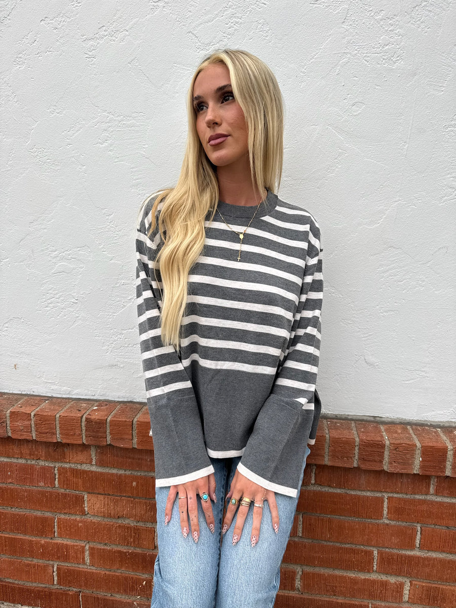 Featuring a long sleeve, horizontal stripped cool grey sweater