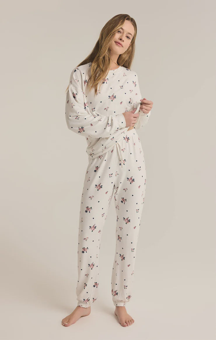 Featuring a floral set, long sleeve crew neck top; mid-rise ankle-length pants in the color sea salt; model is wearing a size small