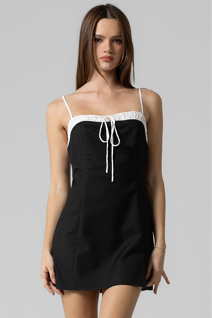 Featuring tie front back zip mini dress with ruching on the top in the color black 