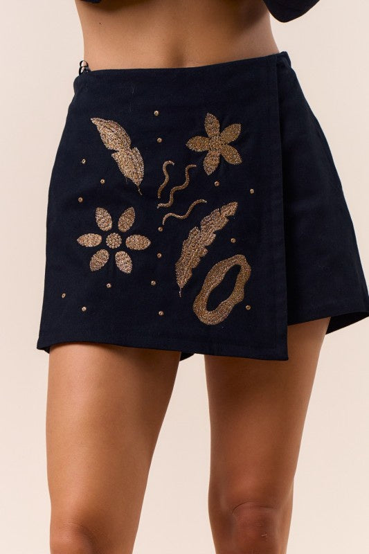 Featuring a black mini skort with gold embroidered wrap