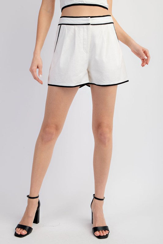 Featuring a high waisted zip up linen short with a contrast hem in the color white and black 