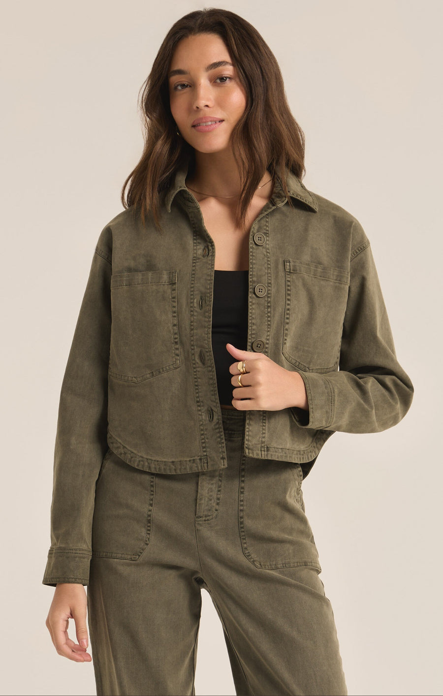 Featuring a cropped button up jacket with two chest pockets and a curved hem in the color grape leaf 