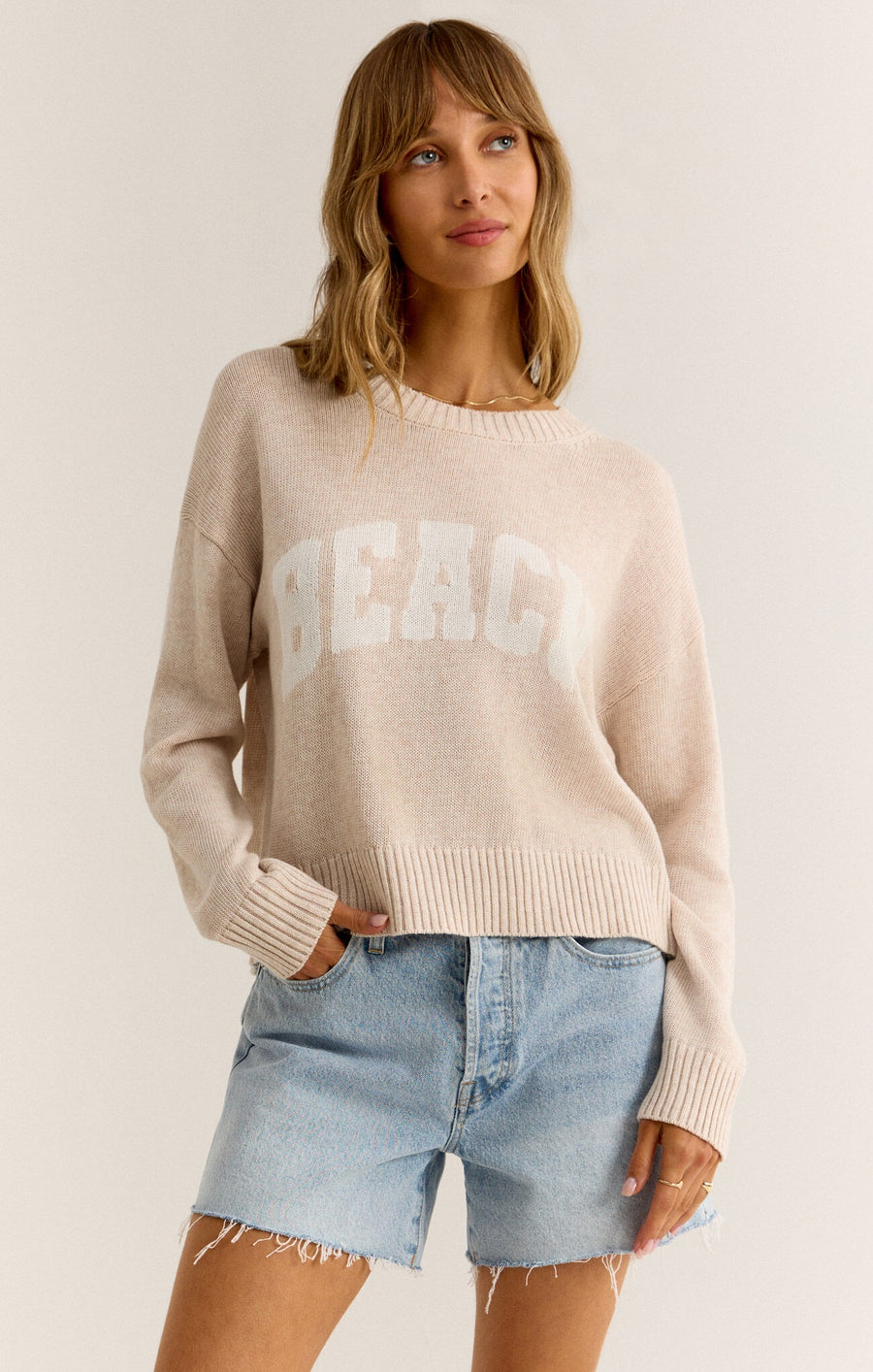 Featuring a slight crop long sleeve light weight sweater in the color light oat meal heather 