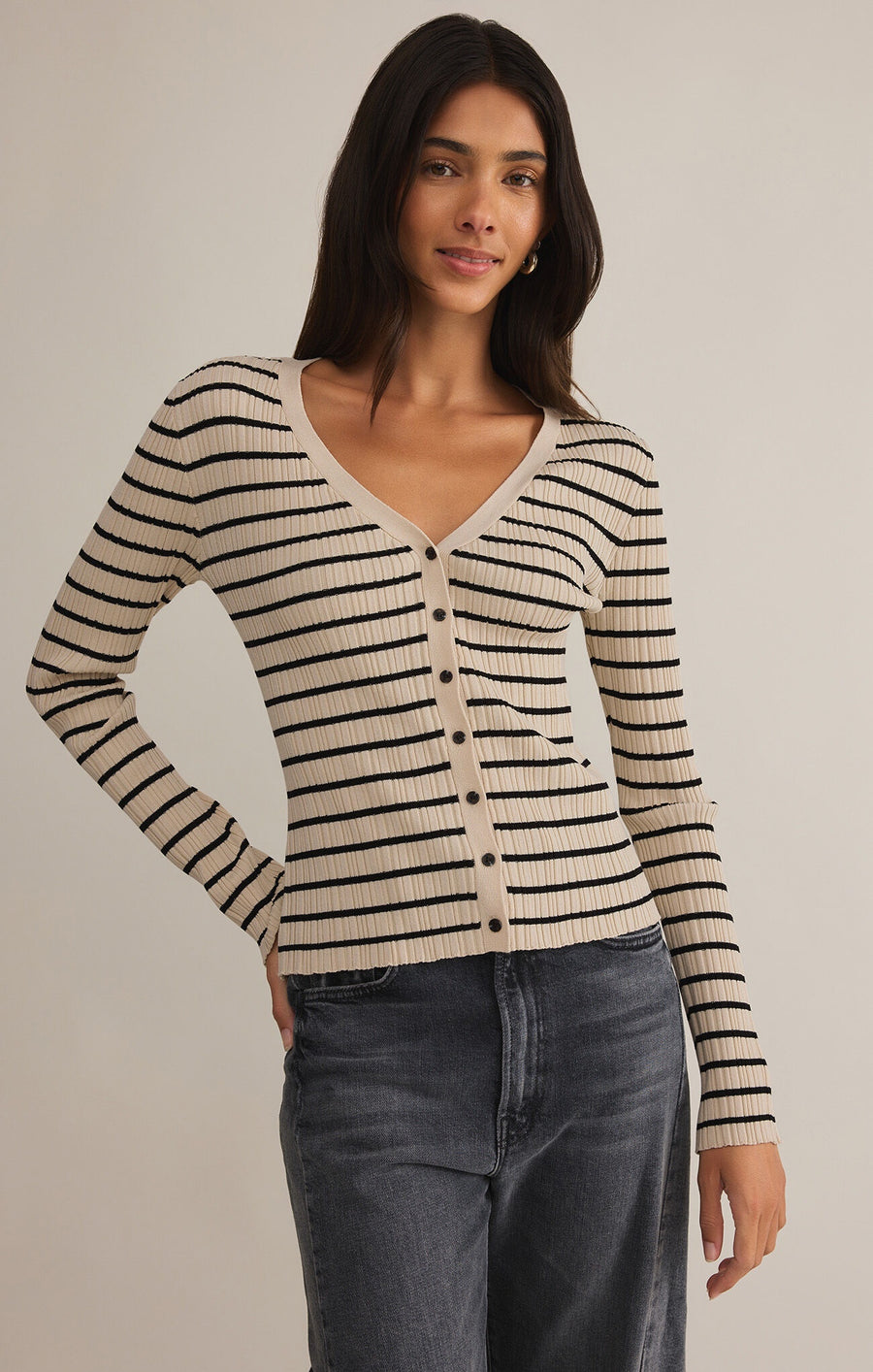 Featuring a V-neck striped button up sweater top in the color sandshell with black stripes 