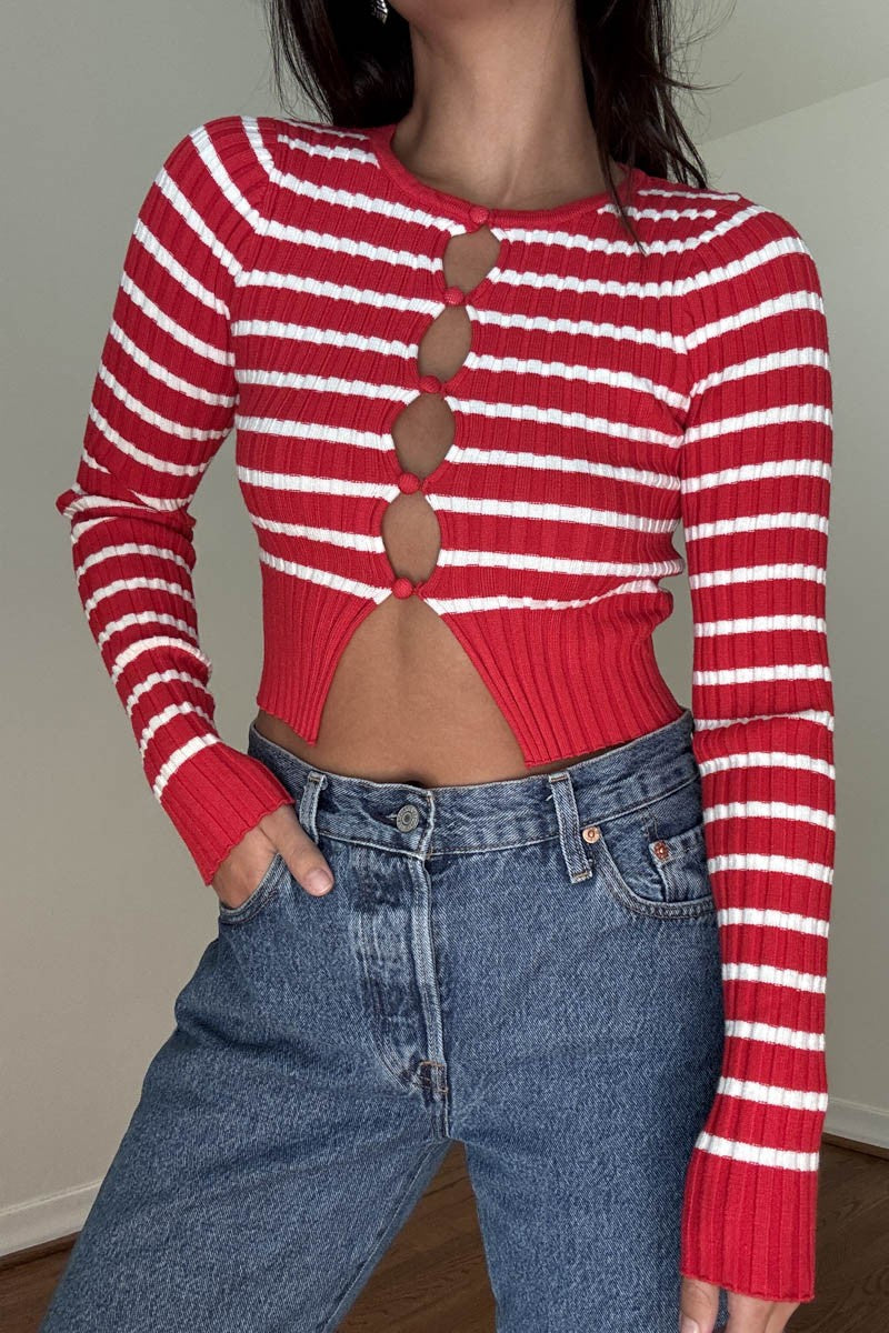 Featuring a cropped knit striped sweater with key hole details along the front in the colors red and white 