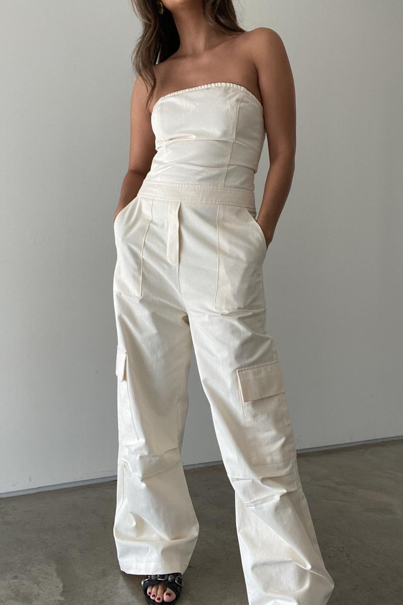 Featuring a strapless cargo jumpsuit fitted through the bust with a wide fit pant in the color cream