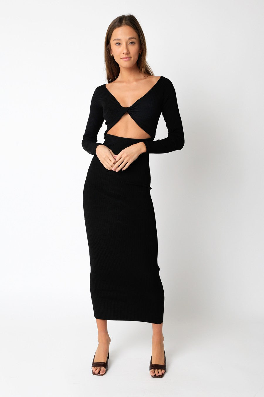 Model is wearing a maxi black dress with an open front cut out and long sleeves. 