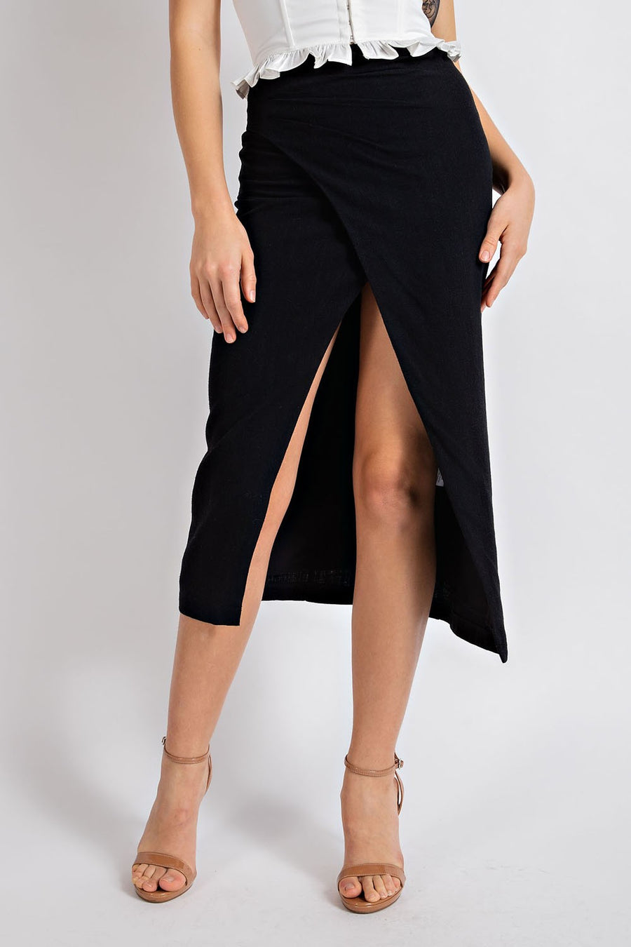 Model is wearing a black linen midi skirt with front slit.
