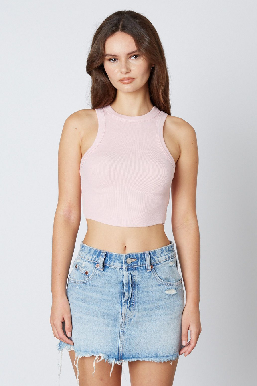 Model is wearing a cropped tank top in the color petal.