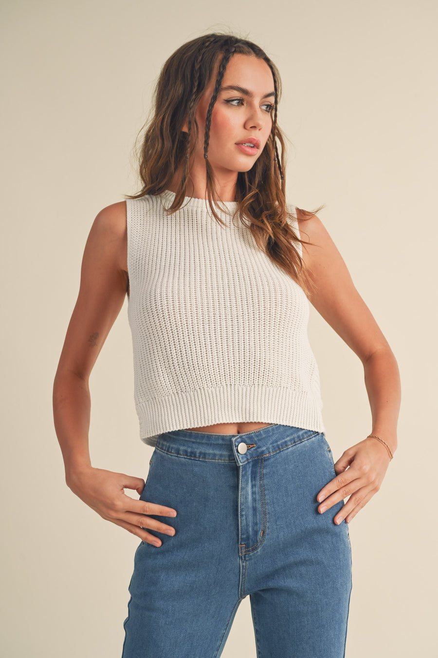 Featuring a cropped knitted sleevless top with a twisted back in the color off white 