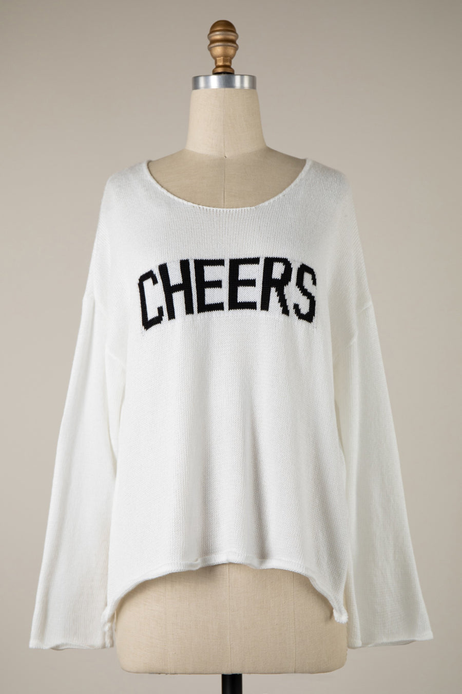 Featuring a light weight sweater with the saying "Cheers" on the front and a wide neckline.