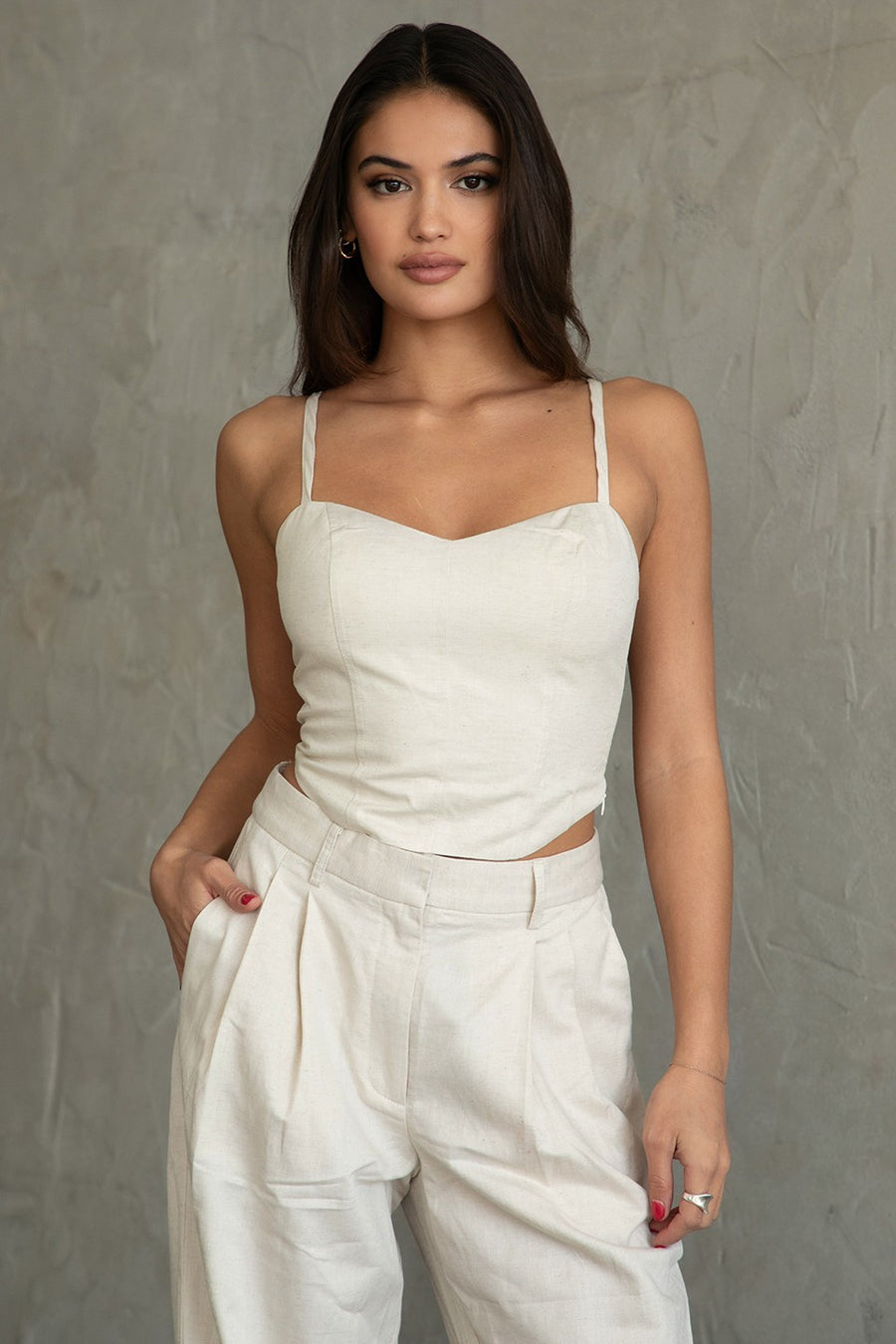 Featuring a cropped linen tank with a side zipper in the color natural