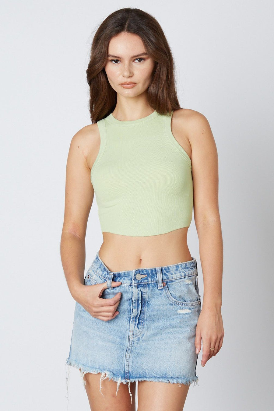 Model is wearing a cropped tank top in the color honeydew.