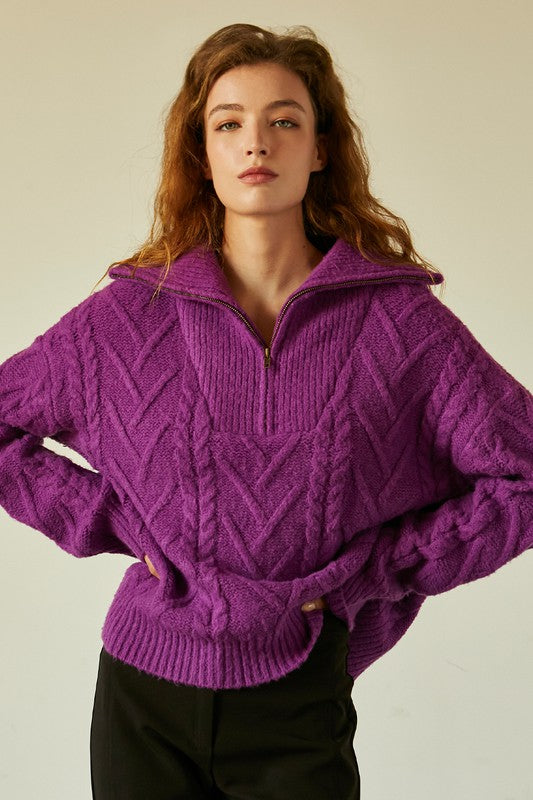 Model is wearing a purple half zip-up sweater.