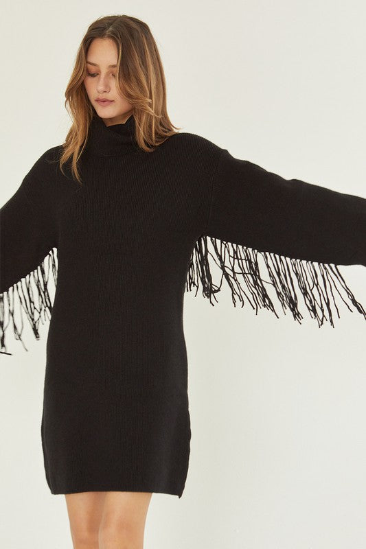 Model is wearing a a sweater turtle neck dress with fringe on the sleeves
