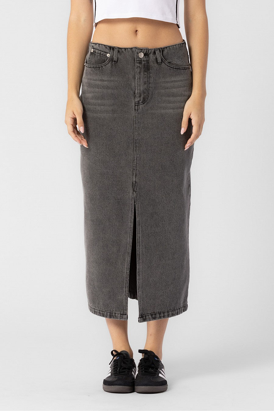 Model is wearing a grey denim midi skirt with front slit.