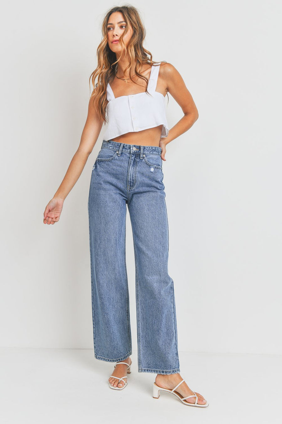 Model is wearing full length medium wash wide leg jeans.
