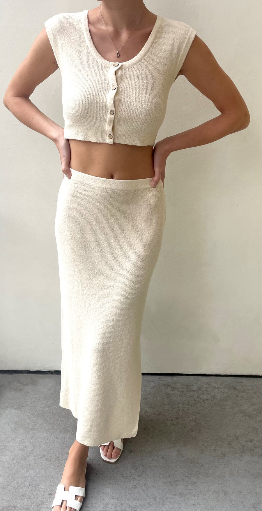 Featuring a light knit midi skirt with a small side slit in the color cream 