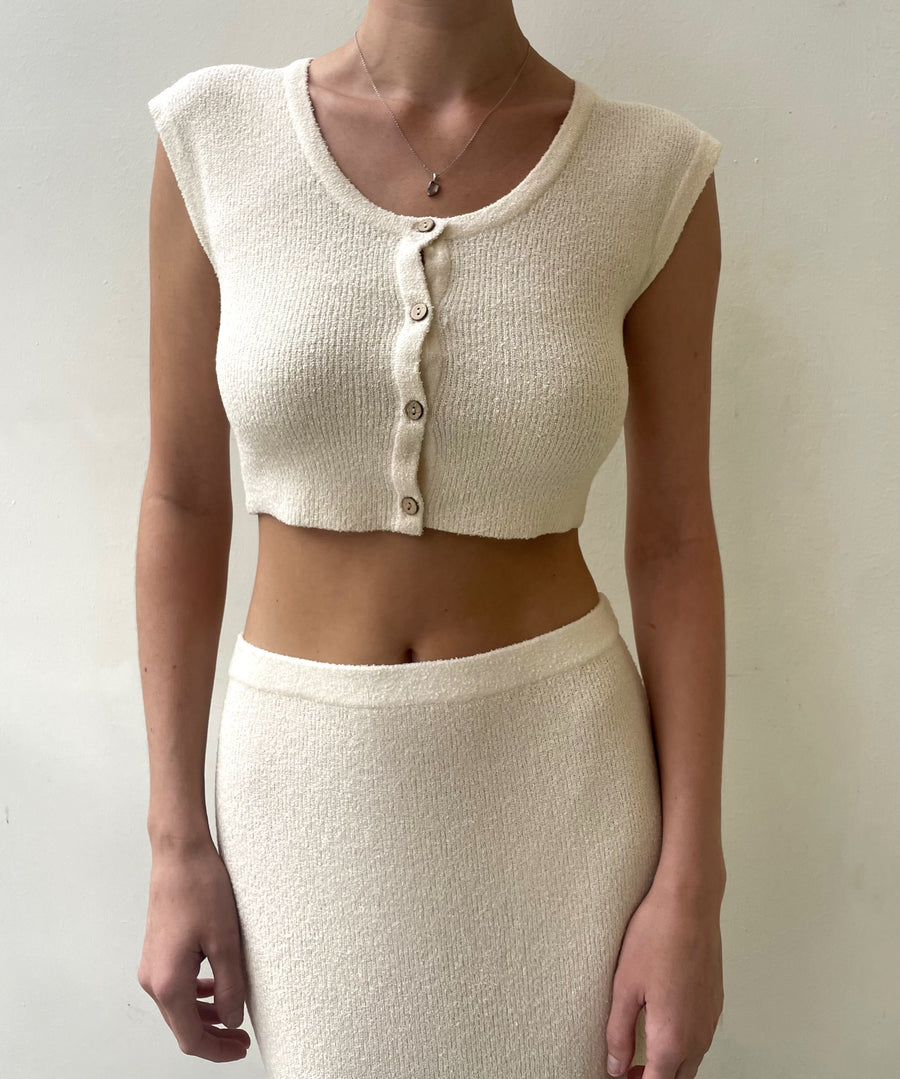 Featuring a cropped short sleeve knit button up in the color cream
