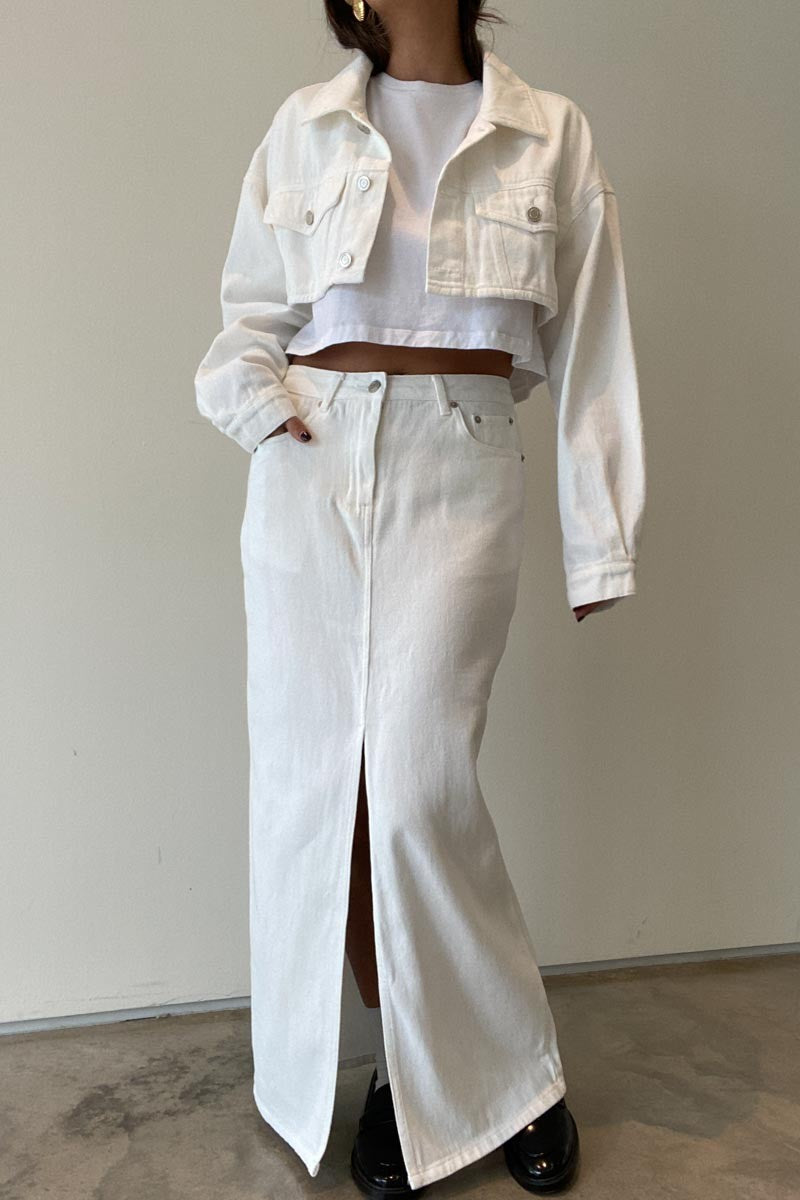 Featuring a maxi denim skirt with a front slit in the color white 
